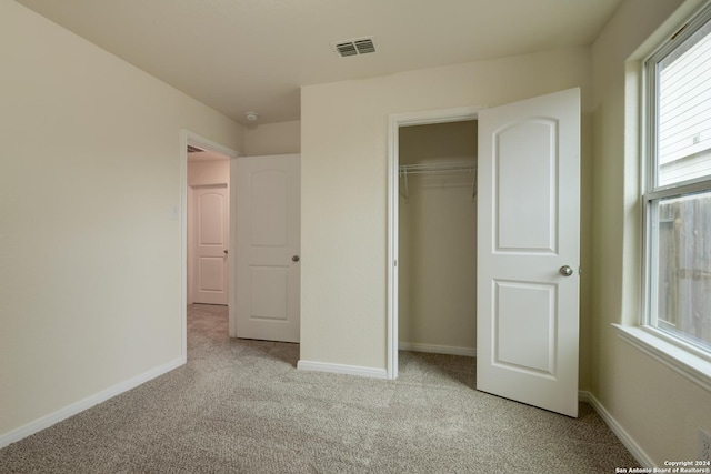 unfurnished bedroom featuring light colored carpet and a closet