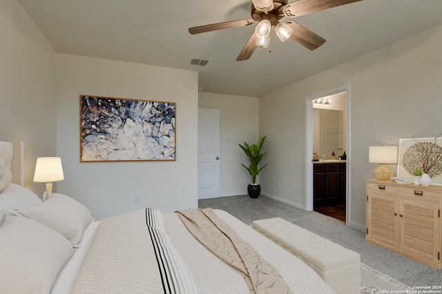 bedroom with light colored carpet, ensuite bath, and ceiling fan