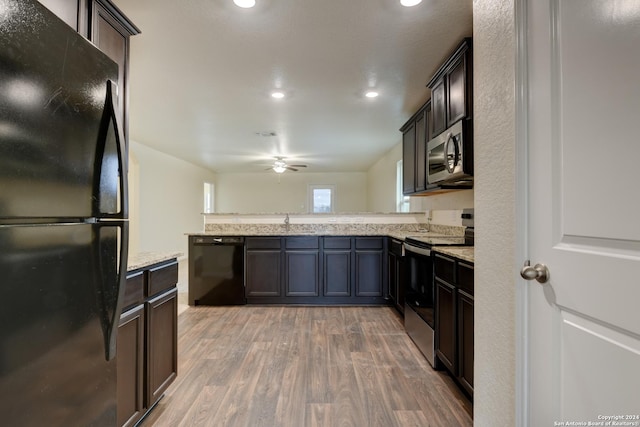 kitchen with black appliances, dark brown cabinetry, kitchen peninsula, and hardwood / wood-style floors