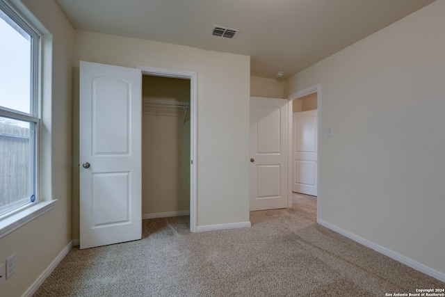 unfurnished bedroom featuring light carpet and a closet