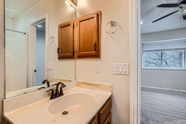 bathroom with a shower, ceiling fan, vanity, and a textured ceiling