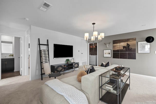 carpeted living room featuring washing machine and clothes dryer and an inviting chandelier