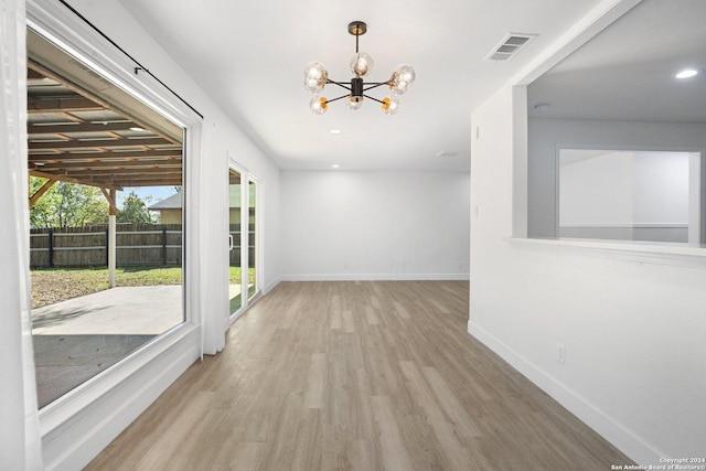 spare room featuring an inviting chandelier and light hardwood / wood-style flooring