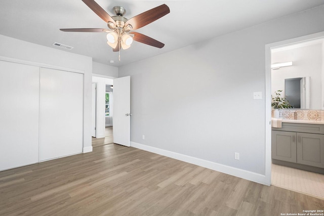 unfurnished bedroom featuring ceiling fan, a closet, ensuite bathroom, and light hardwood / wood-style flooring