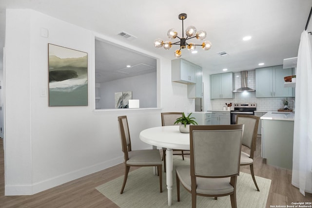 dining area with sink, an inviting chandelier, and light wood-type flooring