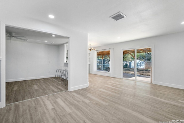 interior space with ceiling fan with notable chandelier and light hardwood / wood-style flooring