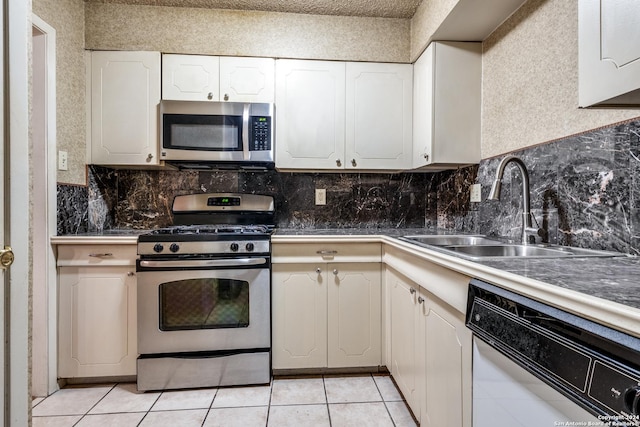 kitchen with light tile patterned floors, stainless steel appliances, white cabinets, and sink