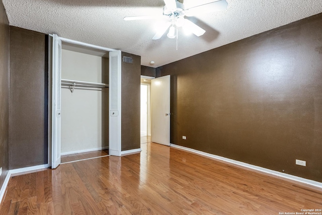 unfurnished bedroom with ceiling fan, wood-type flooring, a closet, and a textured ceiling