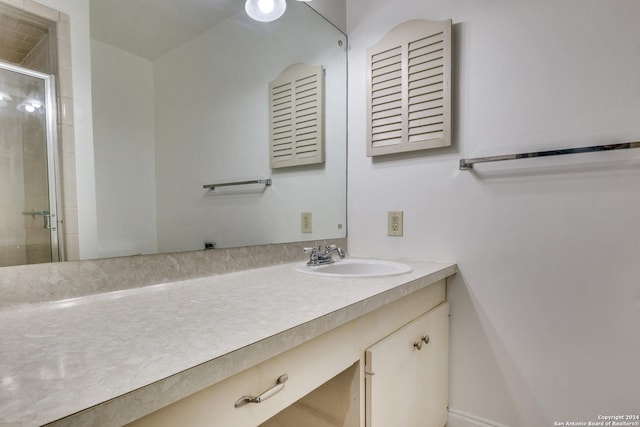 bathroom featuring a shower with shower door and vanity