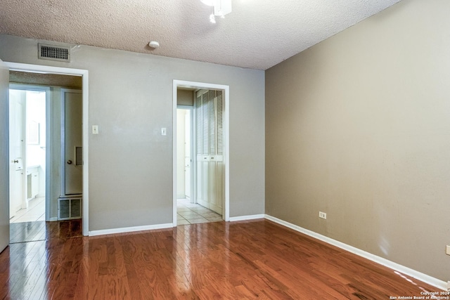 unfurnished room with a textured ceiling and light wood-type flooring