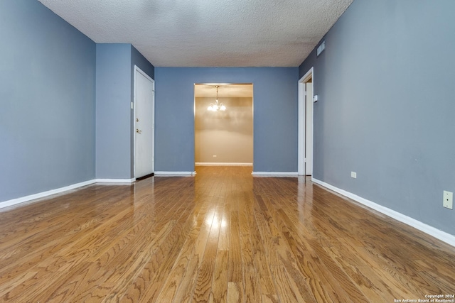 unfurnished room with a textured ceiling, light hardwood / wood-style flooring, and a notable chandelier