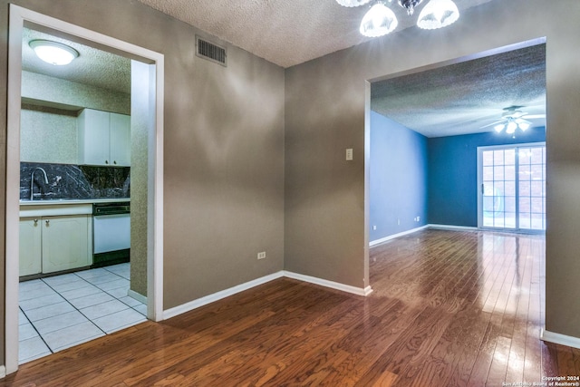 unfurnished room featuring sink, a textured ceiling, and light hardwood / wood-style floors