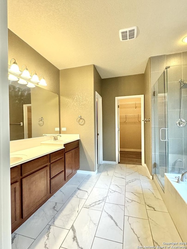 bathroom featuring separate shower and tub, vanity, and a textured ceiling