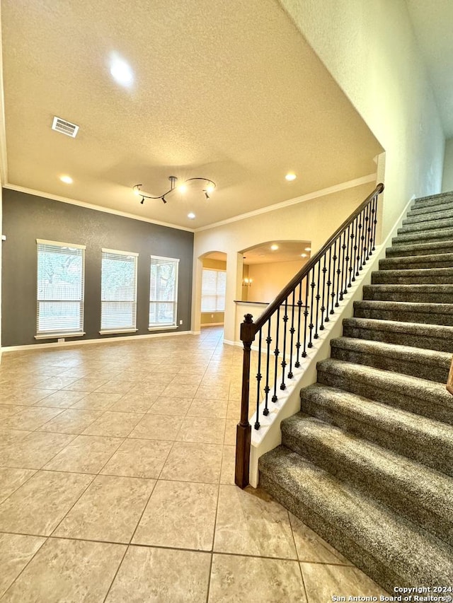 tiled foyer entrance featuring a textured ceiling and ornamental molding