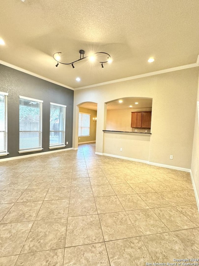 unfurnished living room with a textured ceiling and ornamental molding