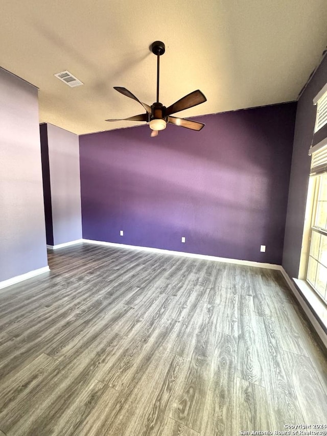 empty room with a textured ceiling, ceiling fan, wood-type flooring, and vaulted ceiling