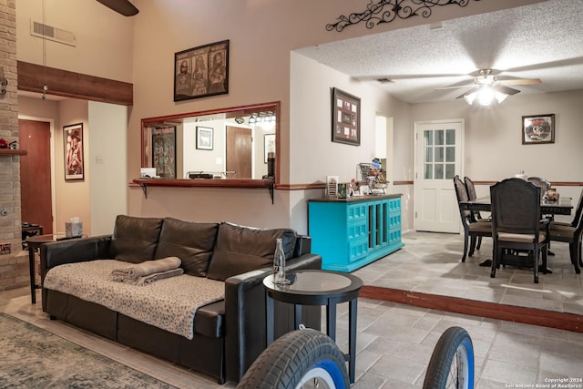 living room featuring ceiling fan, a fireplace, and a textured ceiling