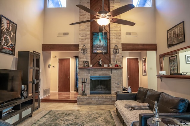 living room featuring a brick fireplace, a wealth of natural light, a towering ceiling, and ceiling fan