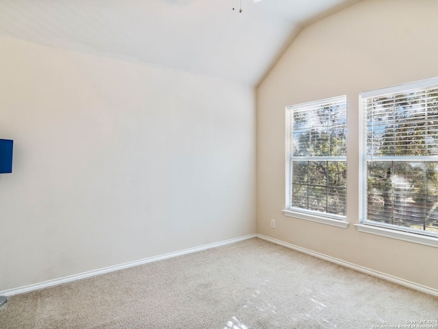 carpeted empty room featuring lofted ceiling