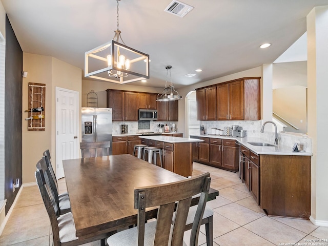 kitchen featuring sink, stainless steel appliances, a chandelier, decorative light fixtures, and a kitchen island