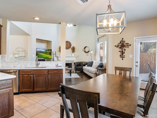 tiled dining space with a fireplace, a notable chandelier, and sink