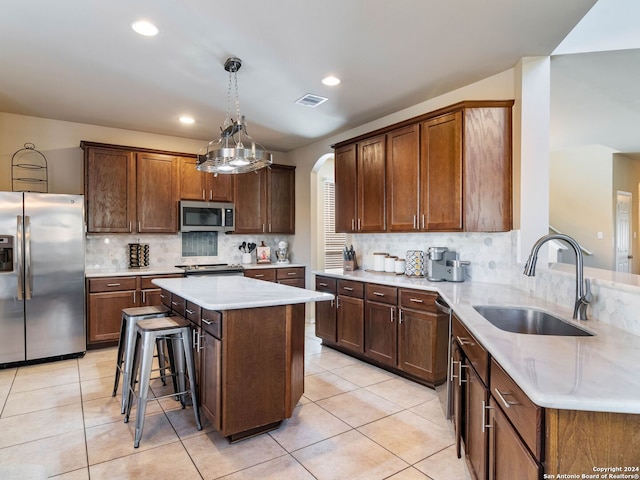 kitchen with sink, a center island, decorative light fixtures, decorative backsplash, and appliances with stainless steel finishes