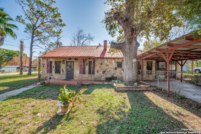 view of front of property featuring stone siding, a chimney, metal roof, and a front yard