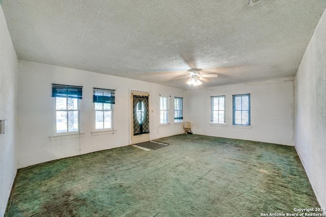 carpeted empty room with plenty of natural light, a textured ceiling, and ceiling fan