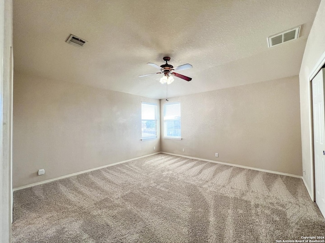 carpeted spare room featuring a textured ceiling and ceiling fan