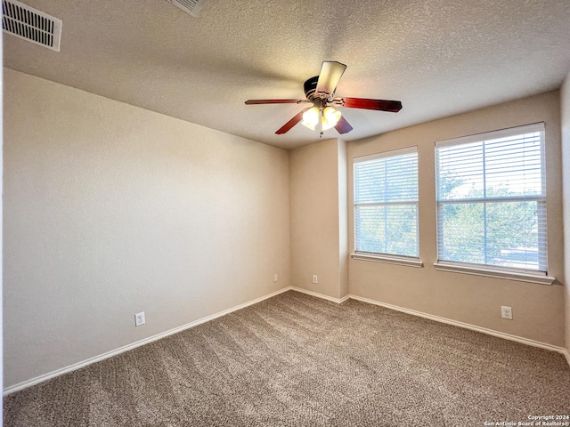 carpeted spare room featuring ceiling fan and a textured ceiling