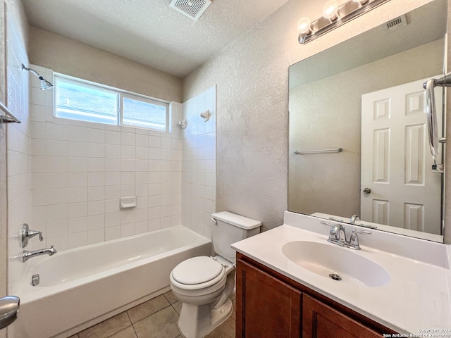 full bathroom with vanity, tile patterned flooring, tiled shower / bath combo, toilet, and a textured ceiling