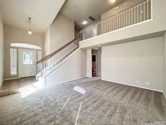 foyer entrance with carpet flooring and a towering ceiling