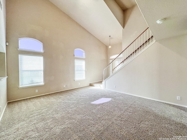 unfurnished living room with carpet floors and high vaulted ceiling