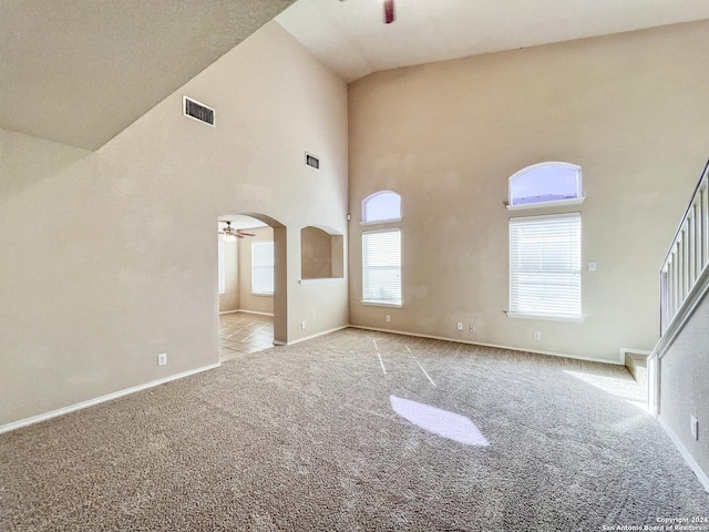 unfurnished living room featuring ceiling fan, high vaulted ceiling, and light colored carpet