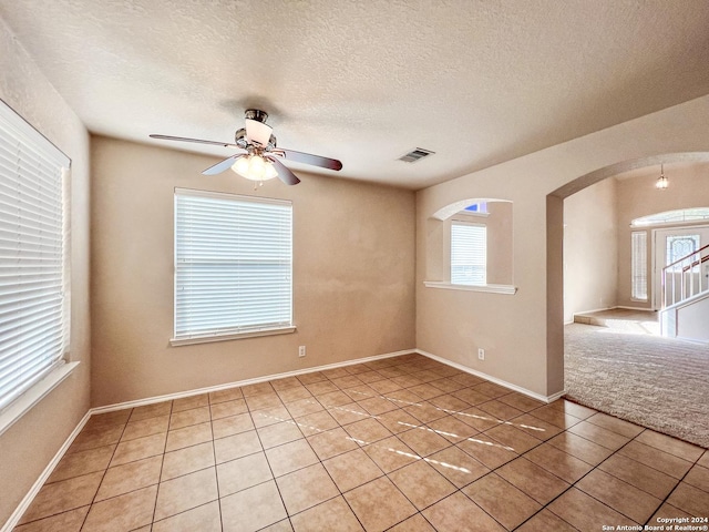 spare room with ceiling fan, light tile patterned floors, and a textured ceiling