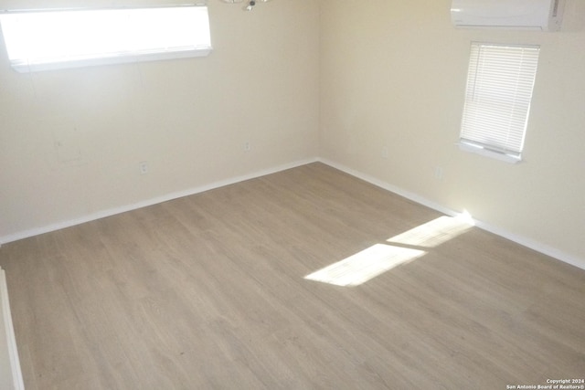 unfurnished room with an AC wall unit and light hardwood / wood-style flooring