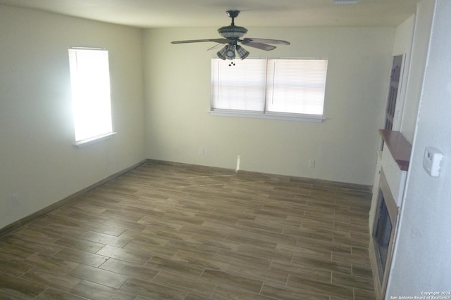 empty room with dark wood-type flooring, ceiling fan, and a healthy amount of sunlight