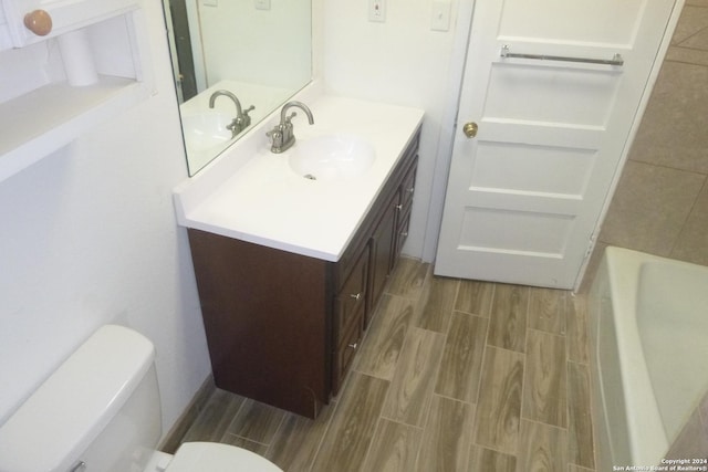 bathroom featuring vanity, toilet, and a tub to relax in