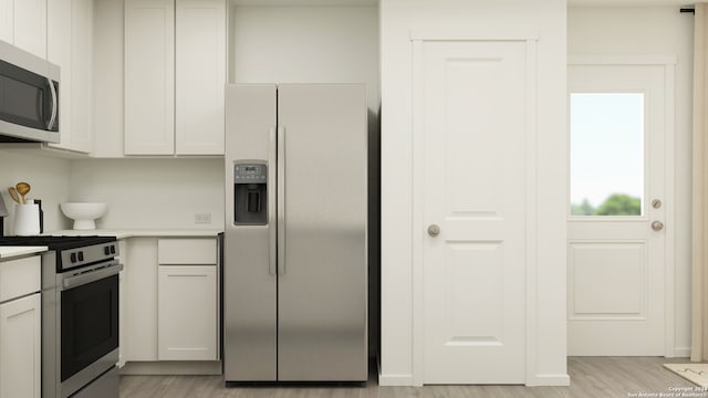 kitchen featuring stainless steel appliances, white cabinetry, and light hardwood / wood-style flooring