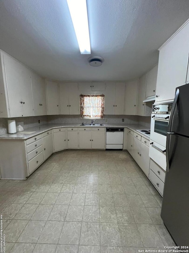 kitchen with a textured ceiling, white cabinetry, sink, and white appliances