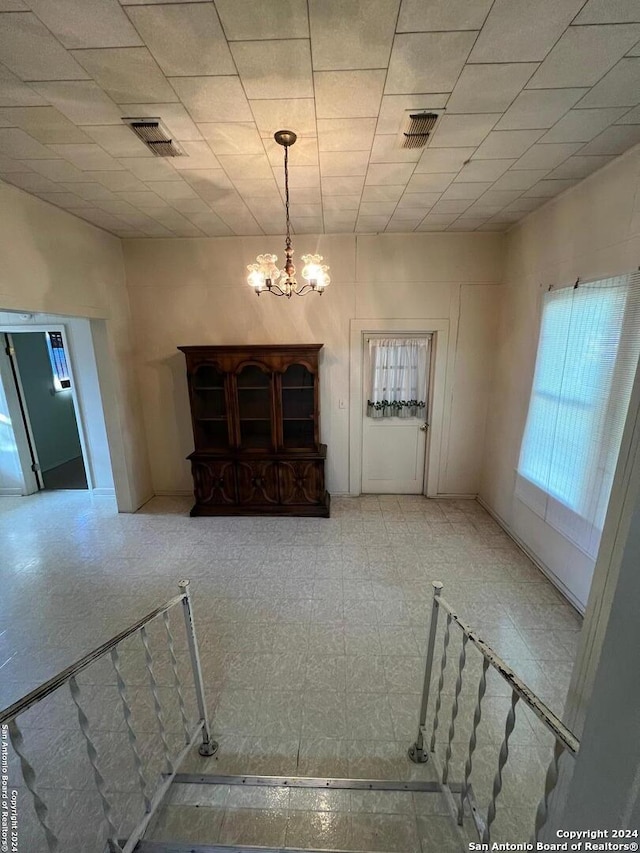 stairway with a paneled ceiling and an inviting chandelier