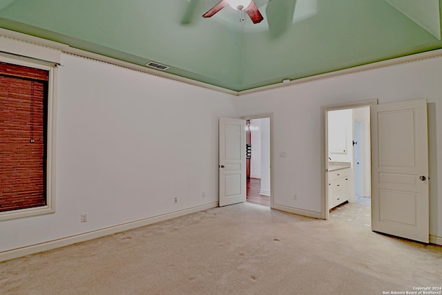 unfurnished bedroom featuring light carpet, a closet, ensuite bathroom, and ceiling fan