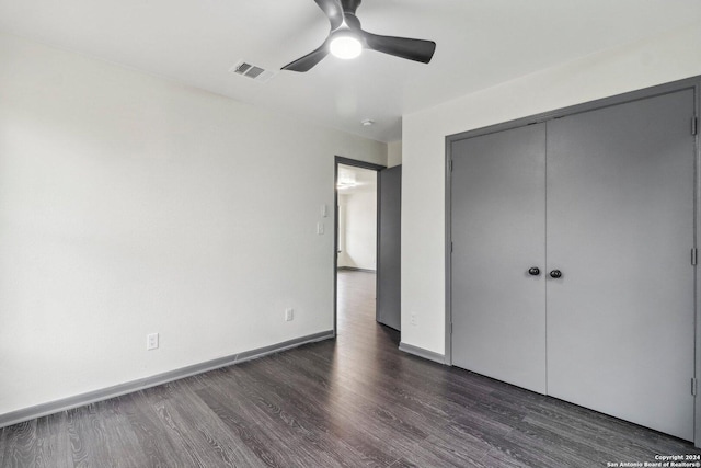 unfurnished bedroom with dark hardwood / wood-style flooring, a closet, and ceiling fan