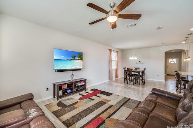 living room with ceiling fan with notable chandelier