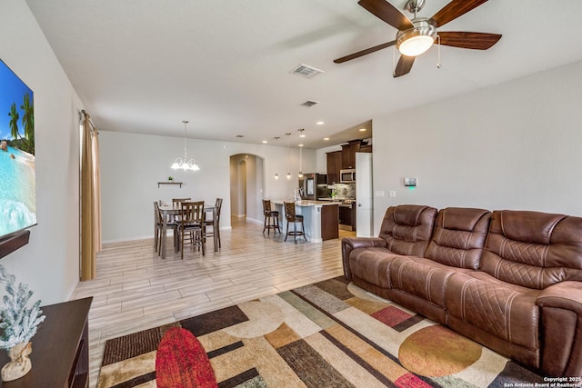 living room featuring ceiling fan with notable chandelier