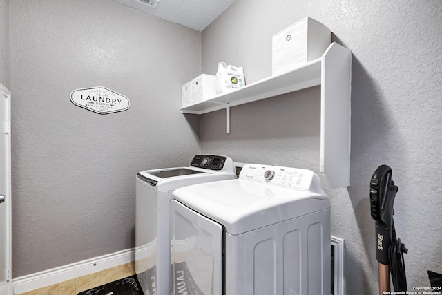 laundry area with light tile patterned flooring, separate washer and dryer, and a textured ceiling