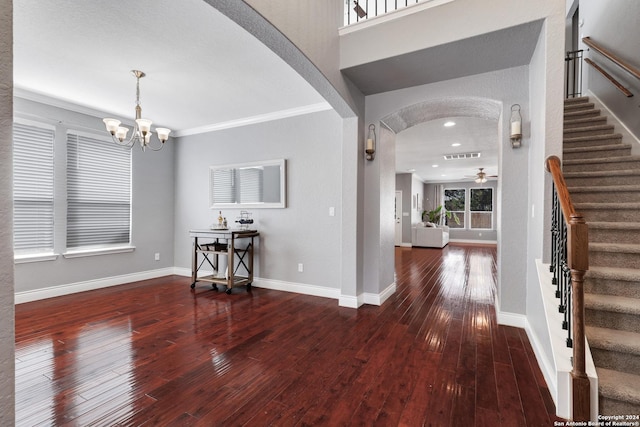 foyer entrance featuring ceiling fan with notable chandelier, dark hardwood / wood-style flooring, ornamental molding, and a textured ceiling