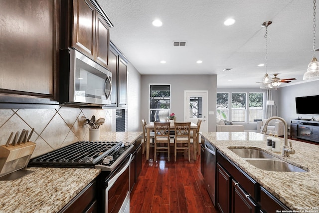 kitchen featuring dark brown cabinetry, stainless steel appliances, dark wood-type flooring, sink, and hanging light fixtures