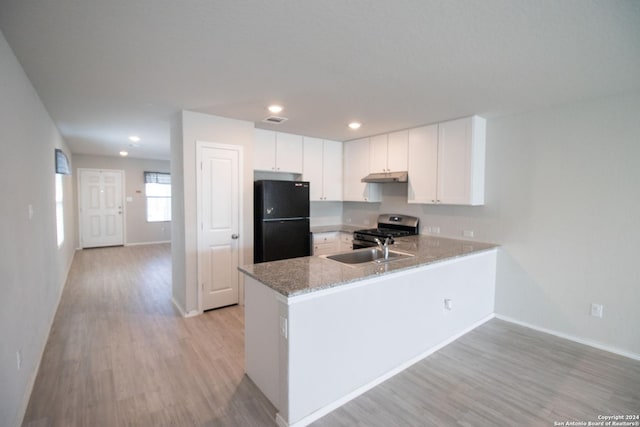 kitchen featuring kitchen peninsula, black fridge, light hardwood / wood-style flooring, white cabinets, and stainless steel gas stove