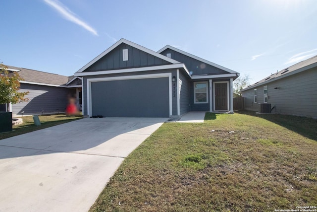 view of front of home with central AC unit, a garage, and a front lawn